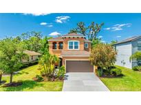 Beautiful two-story home with a well-manicured lawn, mature trees, and a two car garage at 6111 Horse Mill Pl, Palmetto, FL 34221