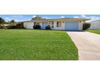 Charming single-story home boasts a well-manicured front lawn and cheerful curb appeal with a blue front door and matching garage at 7301 12Th W Ave, Bradenton, FL 34209