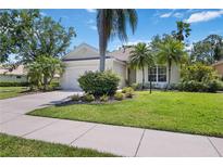 Charming single-story home featuring a well-manicured lawn, lush tropical landscaping, and an attached two-car garage at 7439 Sea Island Ln, University Park, FL 34201