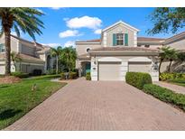 Charming townhouse with a brick driveway, manicured landscaping, and a two-car garage at 7470 Botanica Pkwy # 201B22, Sarasota, FL 34238