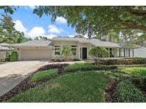Charming home featuring a lush, well-manicured front yard with mature trees and landscaping at 1046 Greystone Ln, Sarasota, FL 34232