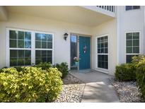 Inviting front entrance with a bright teal door, lovely plants, and decorative touches at 400 Laurel Lake Dr # 104, Venice, FL 34292