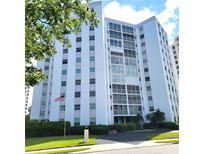 Stunning exterior shot of a white condo building, showcasing lush landscaping and an American flag at 435 S Gulfstream Ave # 605, Sarasota, FL 34236