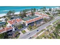 Stunning aerial view of beachfront condos with tennis courts, lush landscaping, and ocean views at 5055 Gulf Of Mexico Dr # 435, Longboat Key, FL 34228