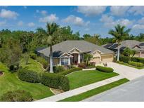 Beautifully landscaped single-story home with a well-manicured lawn, mature palms, and a two-car garage at 5603 90Th Avenue E Cir, Parrish, FL 34219