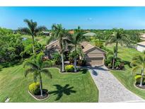 Beautifully landscaped home featuring lush green grass, palm trees, and a paver driveway at 618 148Th Ne Ct, Bradenton, FL 34212