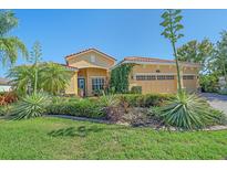 Charming home featuring a terra cotta roof, lush landscaping, and verdant lawn at 6600 Horned Owl Pl, Sarasota, FL 34241