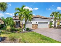 Beautiful home with a tile roof, manicured landscaping, brick driveway, and a three-car garage at 13902 Messina Loop, Bradenton, FL 34211