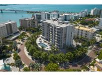 Stunning aerial view of modern condo building with pool, lush landscaping, and bay views at 325 Golden Gate Pt # 1004, Sarasota, FL 34236