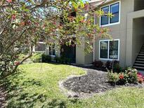 Tan condo building with lush green lawn and landscaping details in front of the screened in patio at 4005 Crockers Lake Blvd # 11, Sarasota, FL 34238