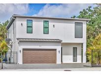 Modern two-story home with a white facade, brown garage door, and well-manicured landscaping at 4112 Swift Rd, Sarasota, FL 34231