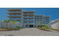 Modern condominium with manicured landscaping and a paved driveway, set against a clear blue sky at 4651 Gulf Of Mexico Dr # 304, Longboat Key, FL 34228