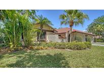 Exterior view of home featuring lush landscaping, a tiled roof, and a well-maintained lawn at 5458 Golf Pointe Dr, Sarasota, FL 34243