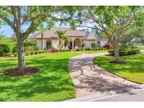 Charming single-story home featuring a well-manicured lawn, beautiful landscaping, and a circular brick driveway at 7408 S Serenoa Dr, Sarasota, FL 34241