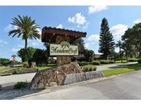 Attractive stone and wood Meadowcroft community sign on a sunny day with a palm tree and lush landscaping at 1431 57Th W St # 1431, Bradenton, FL 34209
