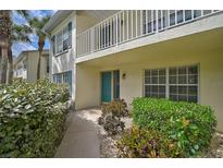 Inviting condo exterior featuring a walkway, manicured shrubbery, and a private balcony with white railings at 208 Silver Lake Dr # 101, Venice, FL 34292