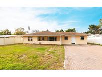 Charming single-story home with a brick driveway and a well-maintained front lawn under a bright blue sky at 2108 Outer Dr, Sarasota, FL 34231
