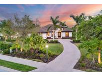 Stunning home exterior with lush landscaping, a paver driveway, and beautiful tropical trees at 3519 Founders Club Dr, Sarasota, FL 34240