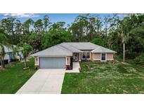 Inviting single-story home with a gray roof, attached garage, and lush green surroundings at 4673 Lummus St, North Port, FL 34286