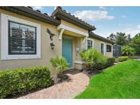 Charming home with a beautiful blue door, lush landscaping, and a welcoming brick path at 5019 Serata Dr, Lakewood Ranch, FL 34211