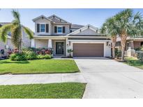 Charming two-story home with manicured lawn, lush landscaping, and a two-car garage at 5749 Sunflower Cir, Sarasota, FL 34238