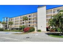 Attractive condo building with tropical landscaping, lush plantings, and visible parking at 6267 Midnight Pass Rd # 306, Sarasota, FL 34242