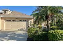 Single-story home with a two-car garage and lush landscaping, including a mature palm tree at 4812 Sand Trap E Cir, Bradenton, FL 34203
