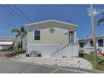 Charming manufactured home with white rock landscaping, palm tree, and decorative metal art piece on the front at 104 1St Ave, Venice, FL 34285
