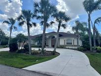 Charming single-story home featuring a well-manicured lawn, mature palm trees, and a circular driveway at 18513 Placid Ave, Port Charlotte, FL 33948