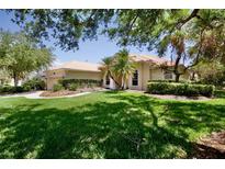 Exterior view showcasing the home's tile roof, lush lawn, landscaping and mature trees at 4713 Sweetmeadow Cir, Sarasota, FL 34238