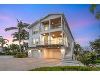 Beautiful two-story beach house with white siding, double balconies, and a two-car garage at dusk at 497 Island Cir, Sarasota, FL 34242
