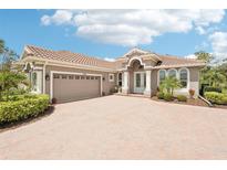 Charming single-story home featuring a tile roof, brick driveway, and well-manicured landscaping at 5480 White Ibis Dr, North Port, FL 34287
