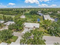 An aerial view showcases this property nestled among trees and overlooking the golf course at 5623 Palm Aire Dr, Sarasota, FL 34243