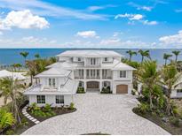 Gorgeous waterfront home showcasing lush landscaping, a brick driveway, and stunning architectural details at 619 Key Royale Dr, Holmes Beach, FL 34217