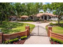Stately home featuring a gated entrance, circular driveway, and lush landscaping, offering curb appeal and privacy at 12224 Garden Lake Cir, Odessa, FL 33556