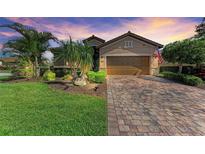Charming single-Gathering home featuring a brick-paved driveway, lush landscaping, and an attached two-car garage at 135 Sweet Tree St, Bradenton, FL 34212