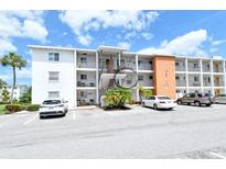 Exterior shot of a three-story condominium building with parking and lush palm trees under a beautiful blue sky at 2227 Sunset Dr # E22, Bradenton, FL 34207