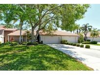 Inviting single-story home with a two-car garage, a well-manicured lawn, mature trees, and lush landscaping at 3954 Wilshire Cir # 165, Sarasota, FL 34238