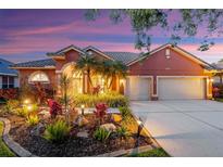 Charming home featuring well-manicured landscaping, a tile roof, and a two-car garage at dusk at 4926 Sabal Lake Cir, Sarasota, FL 34238