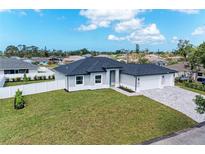Well-manicured lawn complements this newly built home featuring a spacious three-car garage and paver driveway at 5322 Syracuse Rd, Venice, FL 34293