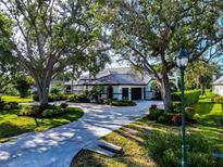Lovely home featuring a circular driveway, two-car garage, manicured landscaping, and mature trees at 600 Eagle Watch Ln, Osprey, FL 34229