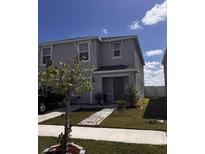 Charming two-story home with well-maintained lawn and walkway to a covered front porch at 615 Sunlit Coral St, Ruskin, FL 33570