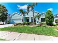 Charming single-story home with a well-manicured lawn, colorful flowerbeds, and lush palm trees at 736 Rosemary Cir, Bradenton, FL 34212