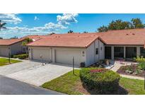 Charming single-story villa with a tile roof, attached garage and walkway leading to the covered screened porch at 892 Country Club Cir # 50, Venice, FL 34293
