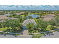 Stunning aerial view of home featuring lush landscaping and a serene lake in a desirable community at 14350 Stirling Dr, Lakewood Ranch, FL 34202