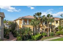 Beautiful two-story townhouse with lush landscaping, palm trees and classic architectural detailing on a sunny day at 1586 Dorgali Dr, Sarasota, FL 34238