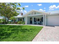 Charming home with a lush green lawn, beautiful landscaping, and inviting front porch seating at 204 75Th St, Holmes Beach, FL 34217