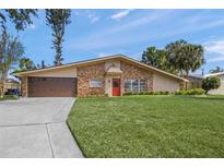 Charming single-story home features a brick facade, well-manicured lawn, and inviting red front door at 2551 Waneta Dr, Sarasota, FL 34231