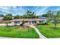Charming single-story home with well-maintained lawn and tropical landscaping under a sunny, partly cloudy sky at 3072 Meyer Dr, Sarasota, FL 34239