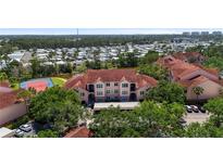 Beautiful condo building with a red tile roof, tennis courts, mature landscaping, and water views at 4138 Central Sarasota Pkwy # 1524, Sarasota, FL 34238